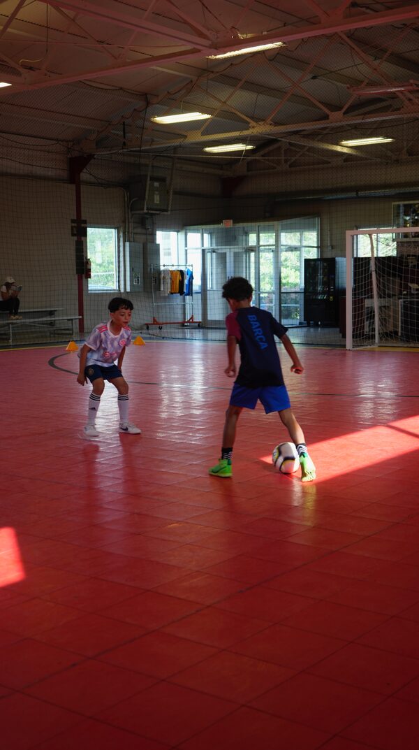 Two young players training on a red futsal court